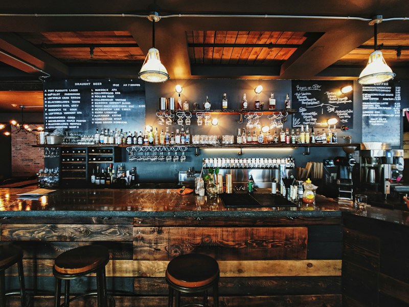 Bartender pouring a cocktail beside a Vanilla POS tablet on the bar